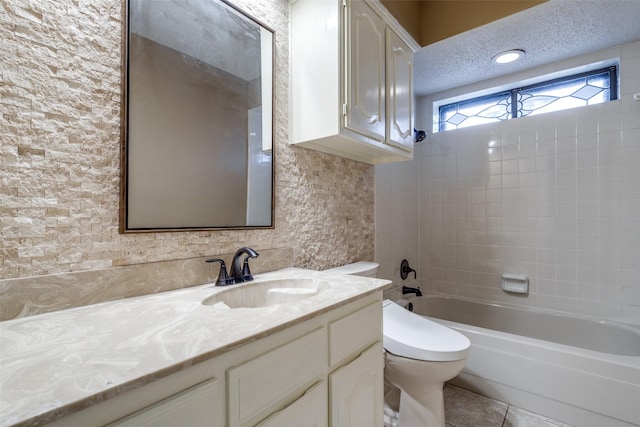 full bathroom with tiled shower / bath, vanity, toilet, tile patterned floors, and a textured ceiling