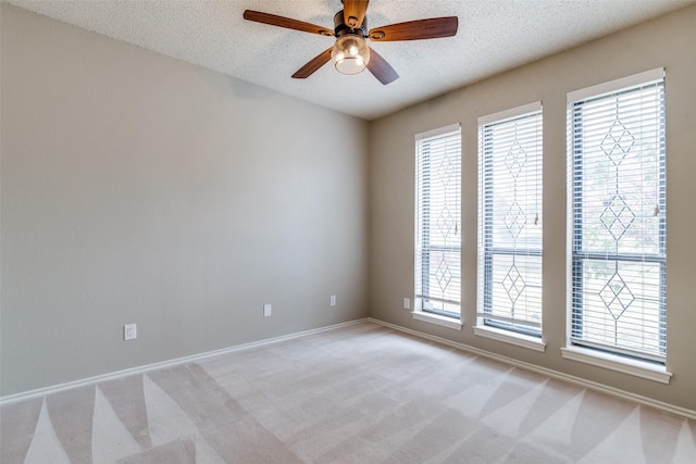 spare room featuring ceiling fan, light colored carpet, and a textured ceiling