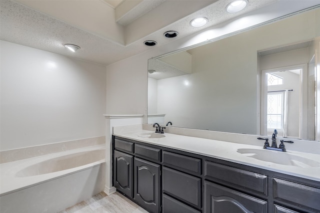 bathroom featuring vanity, a bath, and a textured ceiling