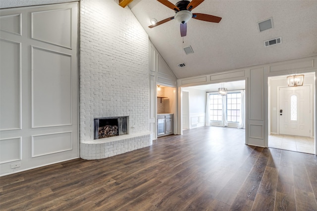 unfurnished living room with dark hardwood / wood-style flooring, a brick fireplace, vaulted ceiling, and a textured ceiling