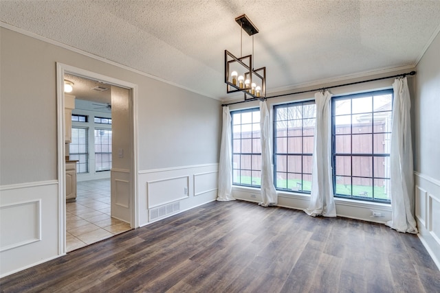 empty room with crown molding, a wealth of natural light, a textured ceiling, and hardwood / wood-style flooring