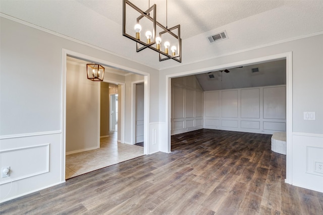 empty room featuring crown molding, dark wood-type flooring, and a chandelier