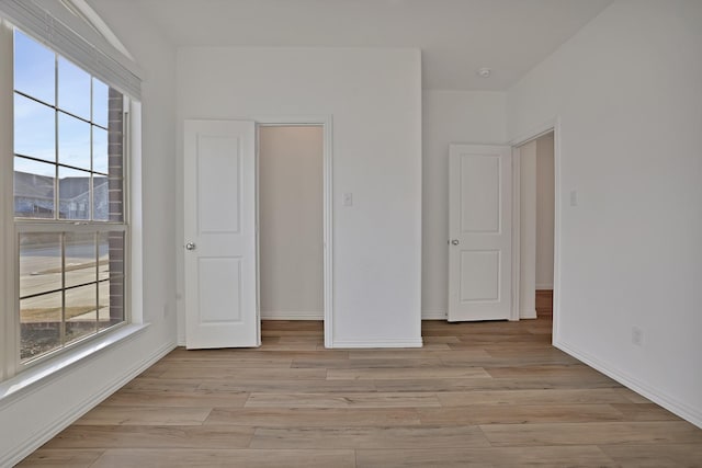 unfurnished bedroom featuring multiple windows and light wood-type flooring