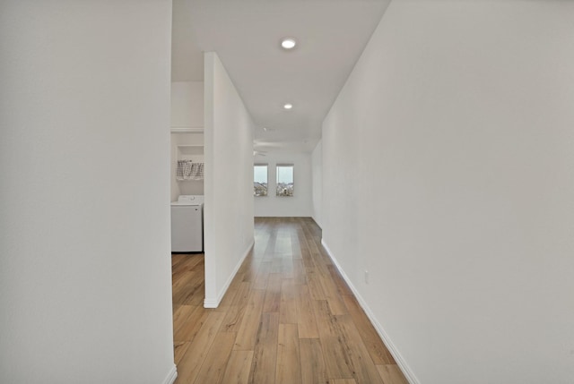 hallway with washer / clothes dryer and light hardwood / wood-style floors