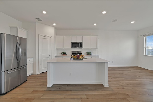 kitchen featuring white cabinetry, backsplash, a center island with sink, and appliances with stainless steel finishes