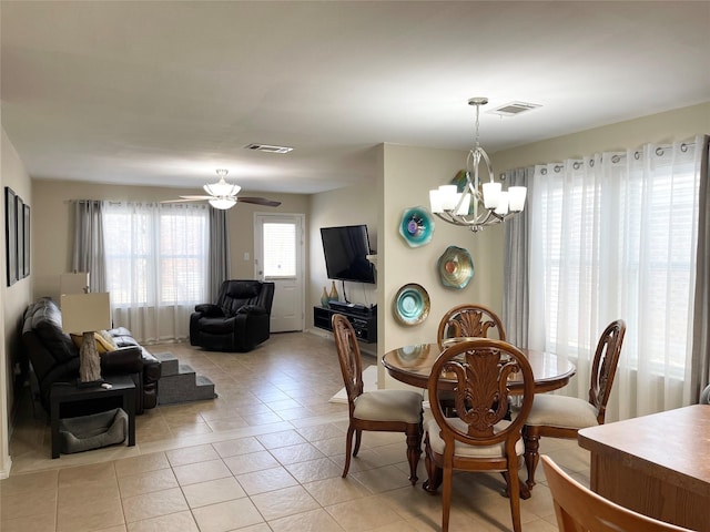 tiled dining room with ceiling fan with notable chandelier