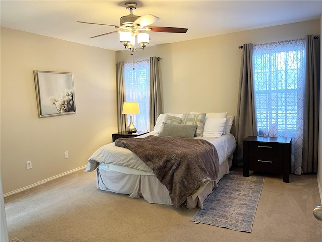 bedroom with ceiling fan, light colored carpet, and multiple windows