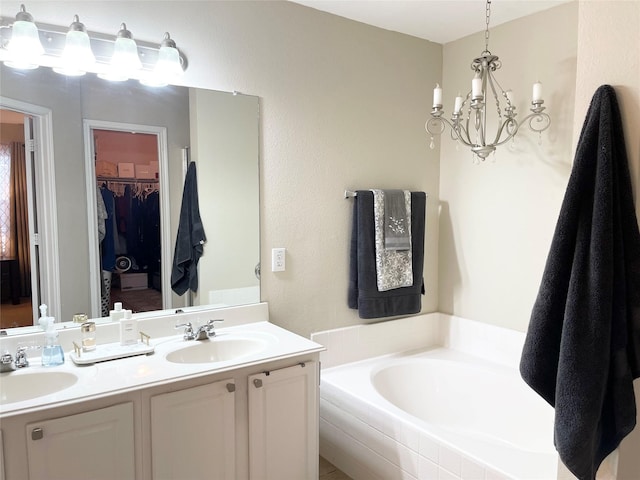 bathroom featuring a relaxing tiled tub, vanity, and an inviting chandelier