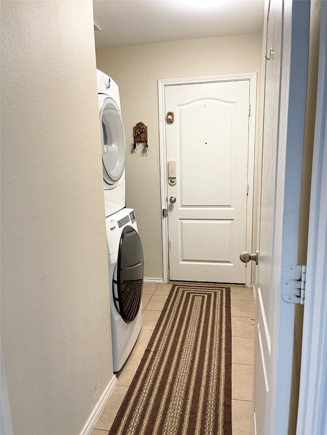 laundry room featuring stacked washer and dryer and light tile patterned floors