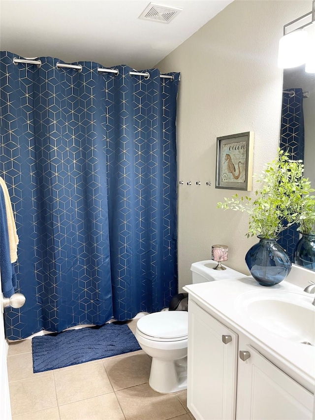 bathroom featuring tile patterned flooring, vanity, toilet, and walk in shower