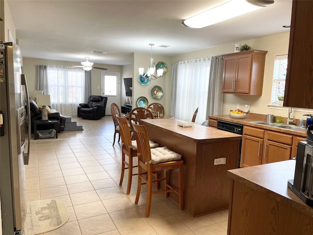 kitchen with light tile patterned flooring, sink, a breakfast bar area, stainless steel fridge with ice dispenser, and a kitchen island