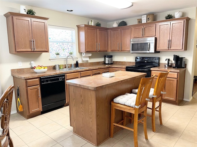 kitchen featuring sink, light tile patterned floors, a breakfast bar area, a center island, and black appliances