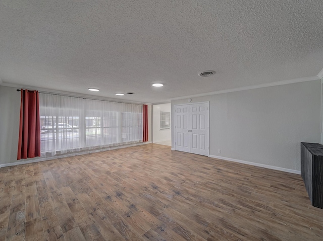 unfurnished living room featuring hardwood / wood-style floors, ornamental molding, and a textured ceiling