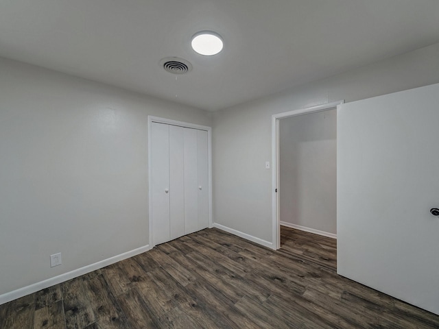 unfurnished bedroom featuring dark hardwood / wood-style flooring and a closet