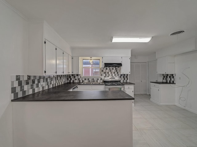 kitchen with sink, stainless steel stove, white cabinetry, backsplash, and kitchen peninsula