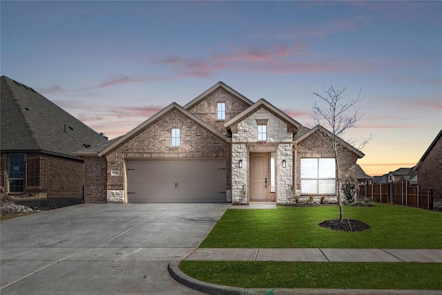 french country style house featuring brick siding, concrete driveway, a lawn, fence, and a garage