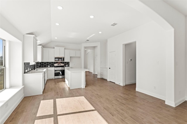 kitchen with visible vents, backsplash, stainless steel appliances, light wood-type flooring, and a sink