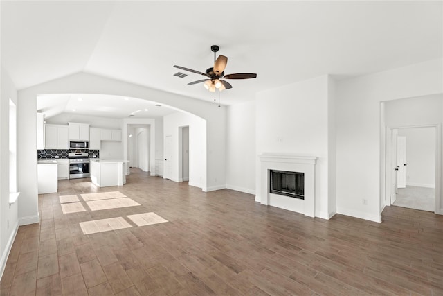 unfurnished living room featuring arched walkways, a fireplace, lofted ceiling, visible vents, and light wood-style flooring