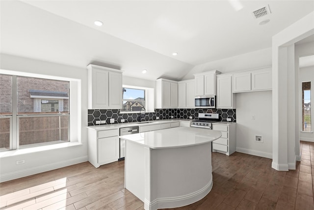 kitchen with wood finished floors, a sink, visible vents, white cabinetry, and appliances with stainless steel finishes