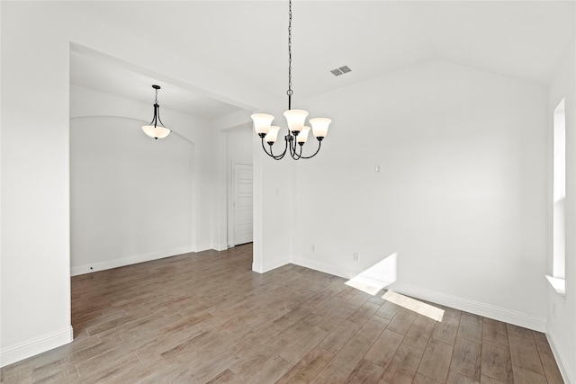 unfurnished dining area with lofted ceiling, wood finished floors, visible vents, and a notable chandelier