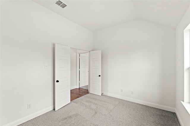 unfurnished bedroom featuring carpet floors, lofted ceiling, visible vents, and baseboards