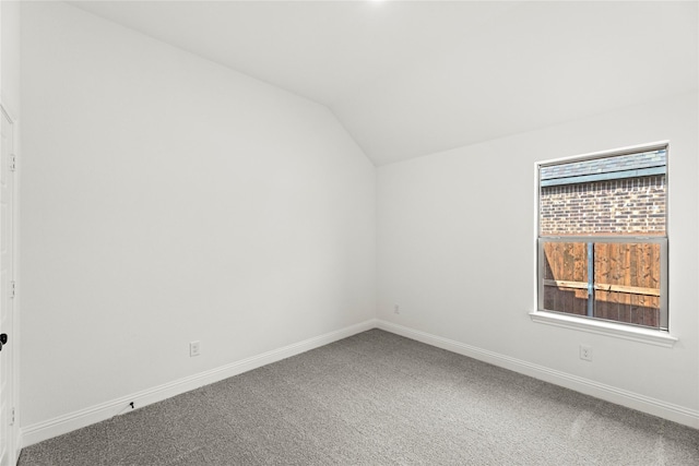 spare room featuring baseboards, vaulted ceiling, and carpet flooring