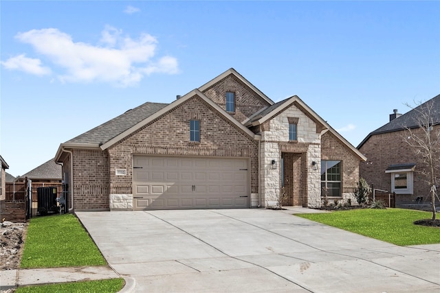 french country home with a garage, brick siding, concrete driveway, stone siding, and a front lawn