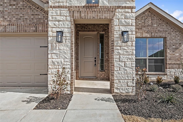 view of exterior entry featuring a garage and brick siding