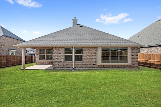 rear view of property featuring a patio area, a lawn, brick siding, and roof with shingles