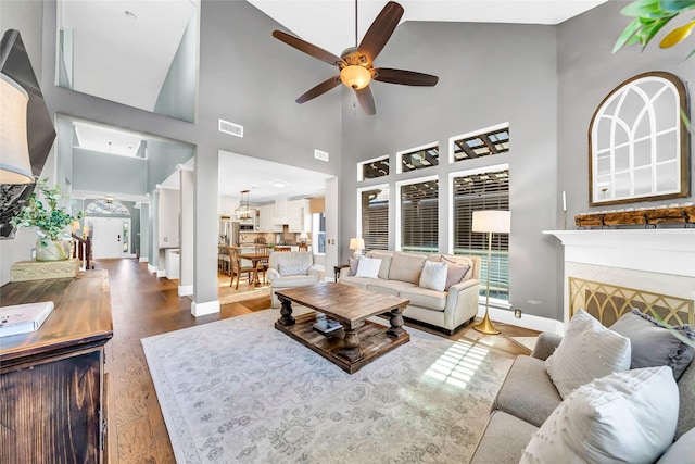 living room featuring hardwood / wood-style floors, a tile fireplace, and ceiling fan