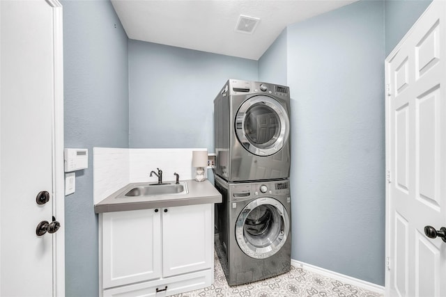 clothes washing area with cabinets, stacked washing maching and dryer, and sink