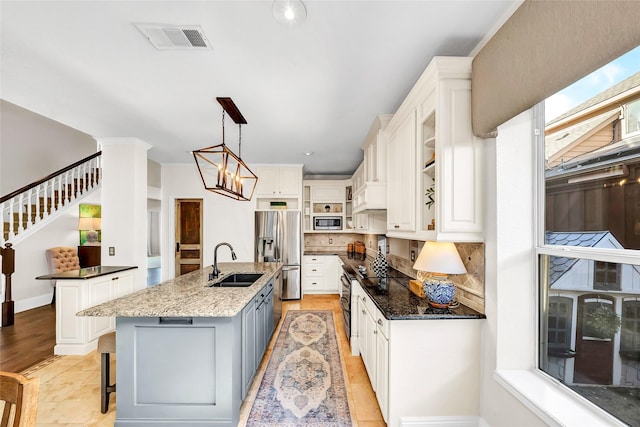 kitchen with a kitchen bar, sink, white cabinetry, an island with sink, and stainless steel appliances