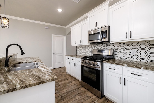 kitchen with dark wood-type flooring, sink, hanging light fixtures, appliances with stainless steel finishes, and white cabinets