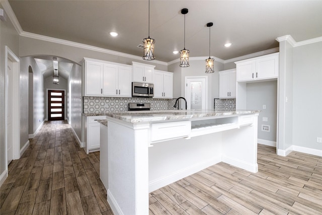 kitchen featuring pendant lighting, white cabinetry, a center island with sink, and appliances with stainless steel finishes