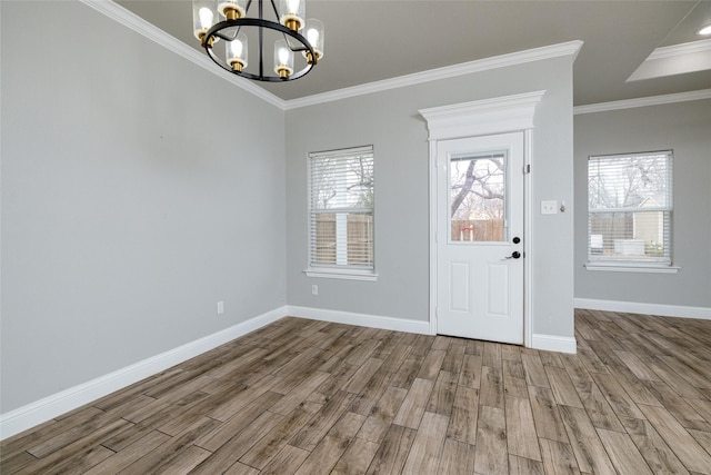 foyer with a wealth of natural light, ornamental molding, hardwood / wood-style floors, and an inviting chandelier