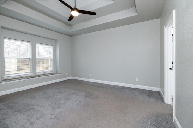 empty room with ceiling fan, a tray ceiling, and carpet floors