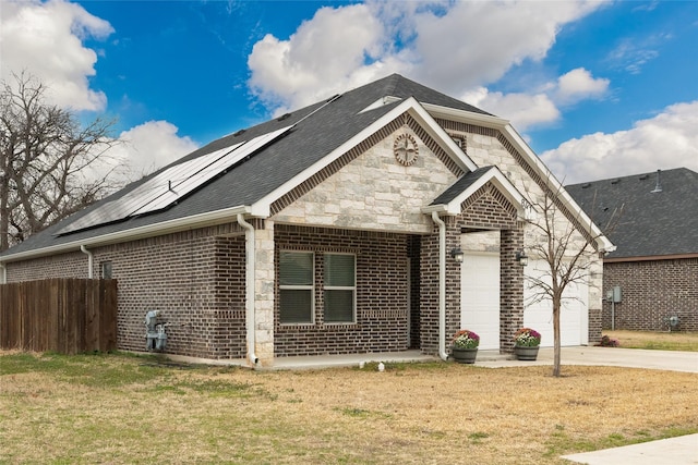 view of front of property featuring a garage, a front yard, and solar panels