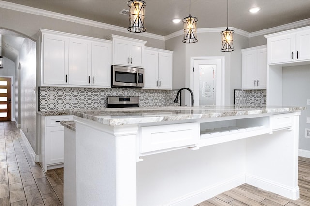 kitchen with white cabinetry, decorative light fixtures, and appliances with stainless steel finishes