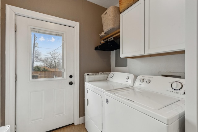 clothes washing area with cabinets, separate washer and dryer, and light wood-type flooring