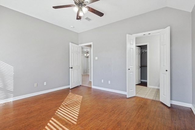 unfurnished bedroom featuring vaulted ceiling, ceiling fan, a spacious closet, and light hardwood / wood-style floors