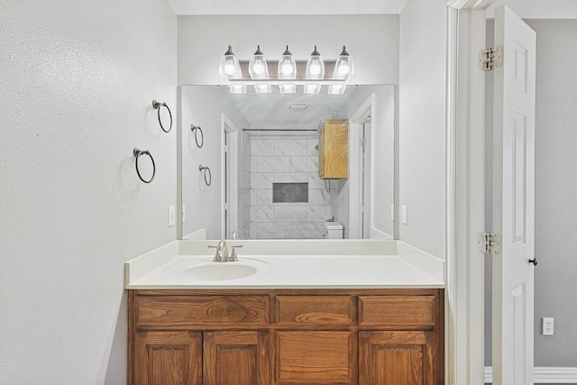 bathroom with vanity, tiled shower, and toilet