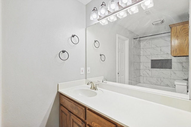 full bathroom featuring tiled shower / bath combo, vanity, and toilet