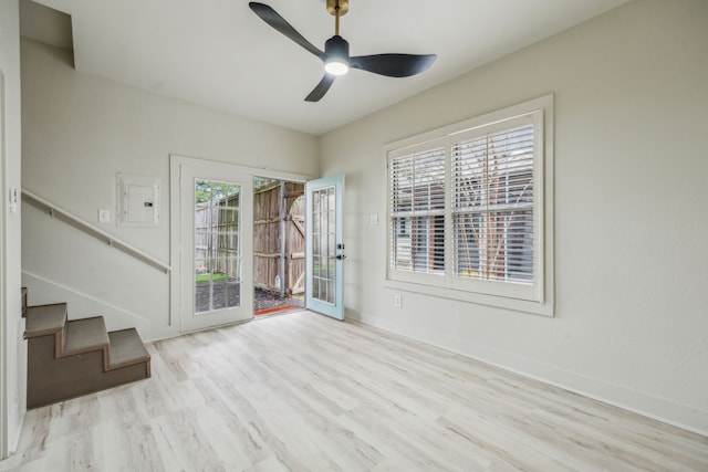 spare room with ceiling fan, electric panel, and light hardwood / wood-style flooring