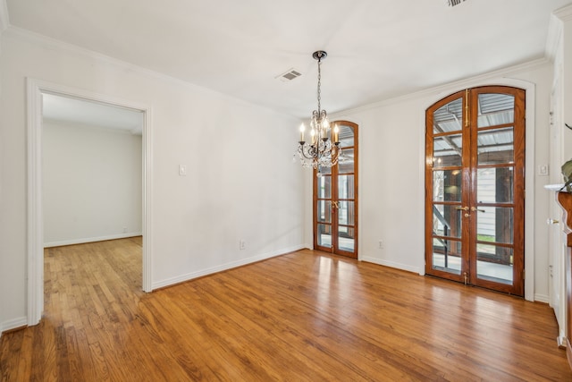 unfurnished dining area featuring light hardwood / wood-style flooring, ornamental molding, french doors, and a chandelier