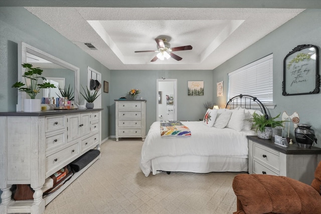 bedroom featuring ceiling fan, a raised ceiling, and a textured ceiling