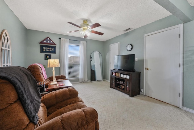 carpeted living room featuring ceiling fan and a textured ceiling