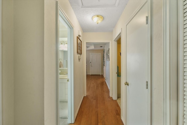 hall featuring light hardwood / wood-style floors and a textured ceiling