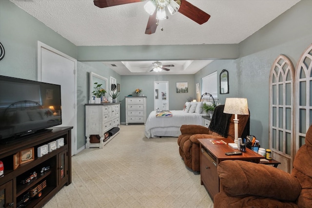 carpeted bedroom featuring ceiling fan, a tray ceiling, and a textured ceiling