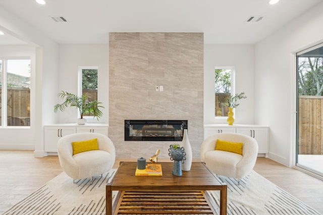 interior space with light wood-type flooring, a tile fireplace, and a wealth of natural light