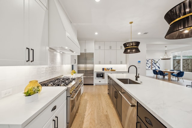 kitchen with pendant lighting, white cabinetry, sink, custom exhaust hood, and high end appliances